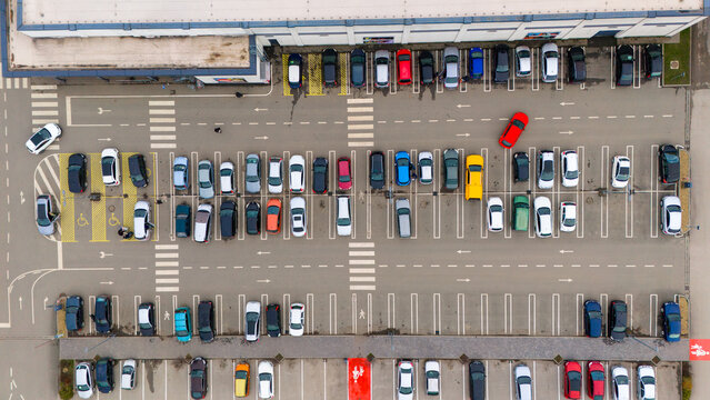 Aerial view of neatly arranged cars in a parking lot with pedestrian crossings near a large building, Sremska Mitrovica, Vojvodina, Serbia.
