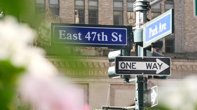 New York Park Avenue, 47 street sign, Manhattan Midtown, United States. Urban road sign in american city, traffic sign in NYC, USA. Building architecture near Grand Central. Flower blossom, flowerbed.