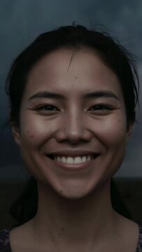 Vertical video: Reacting to camera gaze, Asian woman smiling slowly in studio, patterned top