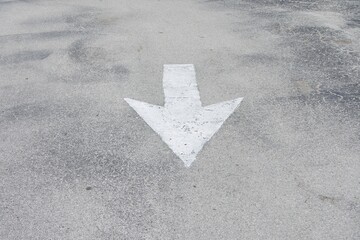 directional arrow sign painted white on asphalt