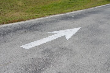 road arrow sign painted white going away