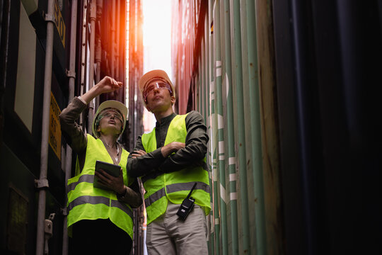 Female logistics supervisor inspecting shipping containers at port terminal, using tablet to manage cargo, safety, and global supply chain operations in international trade.