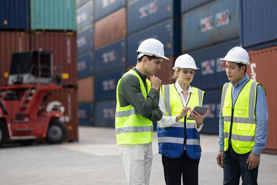 Logistics team using tablet to plan cargo shipment at container yard, coordinating global supply chain, transportation and distribution with safety and teamwork in modern industrial port.