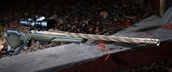 Rifle with a spiral fluted barrel over a large board outdoors