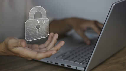 Cyber security safeguards data and systems. Hands on a laptop with a digital padlock icon represent internet privacy, encryption, and protection against hackers in a modern workspace