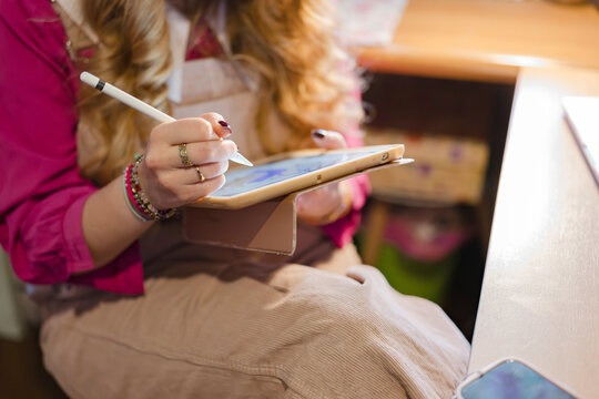 A person uses a stylus to draw on a tablet, showcasing digital art creation and modern technology.
