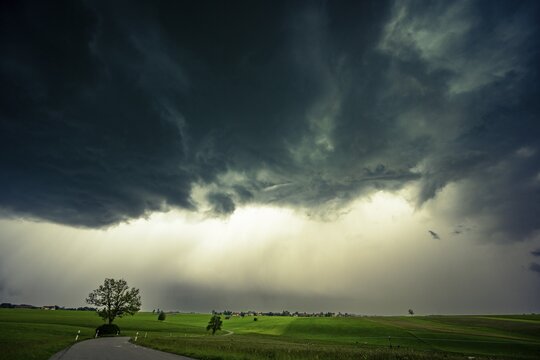 Road and meadows with thunderstorm sky in the background, Eggental, Ostallg&auml;u, Swabia, Bavaria, Germany