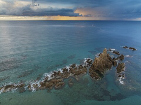 The reef Arrecife de las Sirenas in the Nature Reserve Cabo de Gata-Nijar, at sunrise with heavy showers in the distance, aerial view, drone shot, Almer&iacute;a province, Andalusia, Spain