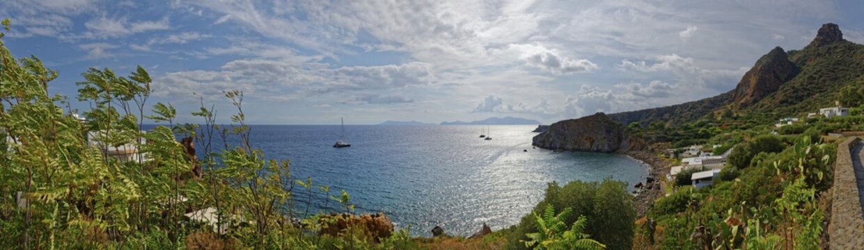 Panoramic view of Isola di Basiluzzo and Vulcano with anchored sailing ships, Panarea, Aeolian Islands, Calabria, Sicily, Italy