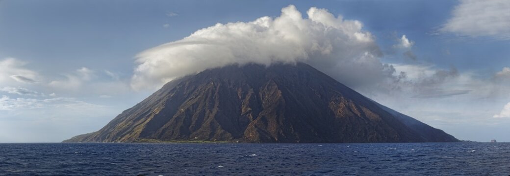 Stromboli volcano and island with bizarre cloudscape, Stromboli, Calabria, Italy