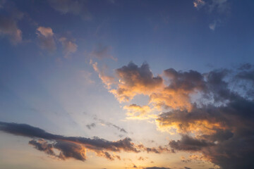 Obraz premium Stunning sunset. Dark clouds blend with bright orange and gold hues against a blue sky.