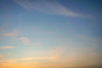 Obraz premium Tranquil twilight sky, likely captured at sunset or sunrise. Thin, fluffy clouds are scattered throughout the area, illuminated by the natural light of the setting or rising sun.