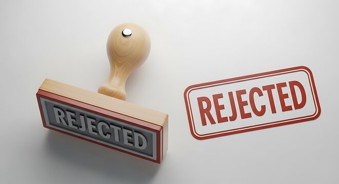A wooden rubber stamp sits beside a distinct red sign both clearly displaying the word rejected on a clean white surface symbolizing refusal or denial in various contexts.