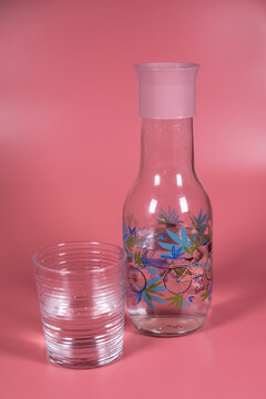 Jarra y vaso de agua sobre fondo de color Salm&oacute;n