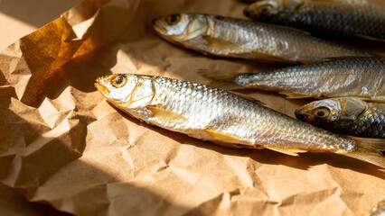 Obraz premium Close up of traditional dried salted fishes on crumpled brown kraft paper, flat lay