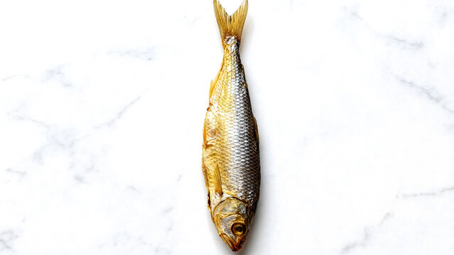 Single dried salted fish vobla on a light marble background, traditional beer snack, top view.