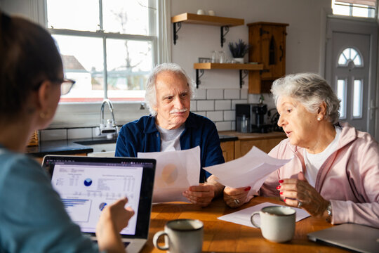 Senior couple reviewing finances with advisor at home kitchen
