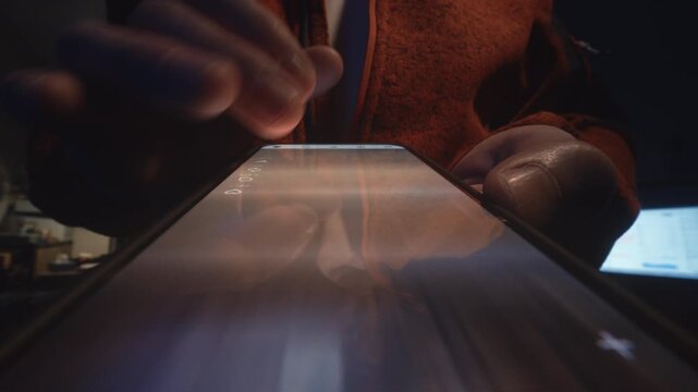 Extreme close-up male finger scrolling smartphone screen in deep darkness at night. Swiping finger, motion blur on phone screen. Evening online browsing, digital content consumption