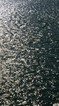 Cinematic sparkling sea surface with a single buoy. Sun glares on dark blue water, minimalist ocean background and calm summer atmosphere.