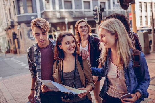 Young friends sightseeing with map on city street