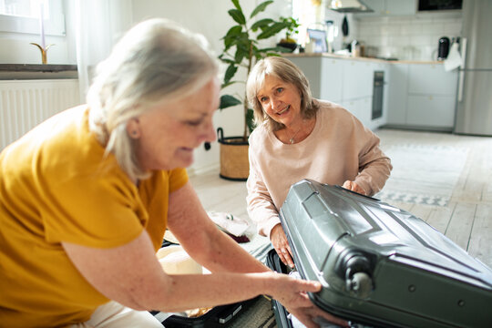 Senior women packing a suitcase in a home kitchen