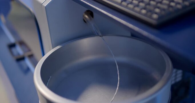 Hand taking thin metal wire into round stainless steel container