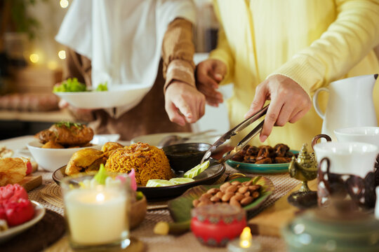 Muslim family serving food together at Ramadan iftar dinner table