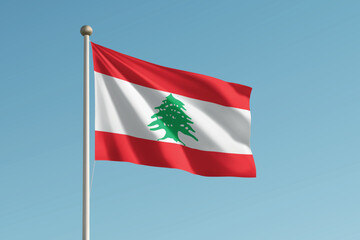 Naklejka premium Lebanon national flag waving on pole against clear blue sky background.