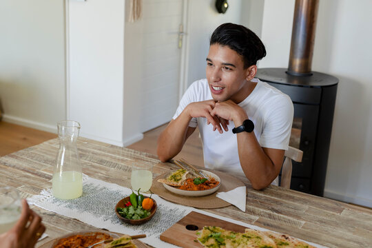 Dining table is holding bowls, flatbread, carafe and glasses near wood-burning stove