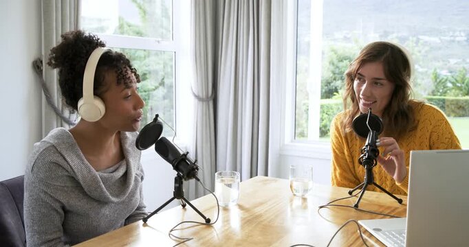 Diverse female co-hosts adjusting headphones and introducing topic on mic while nodding at home