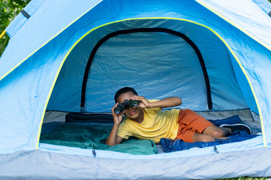 Blue dome tent is framing binoculars, green sleeping bag and dark blue mat on grass