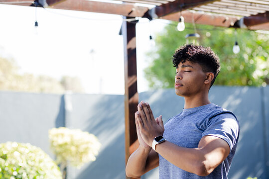 African American man meditating under pergola in athletic tee, smartwatch on wrist, copy space