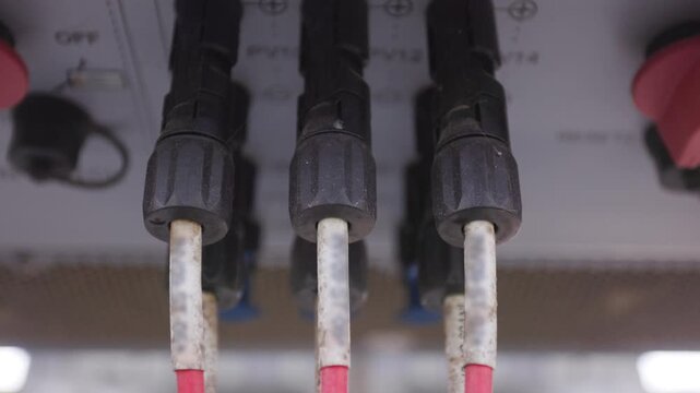 Close-up of MC4 connectors and DC solar cables connected to string inverter in a large scale PV system.