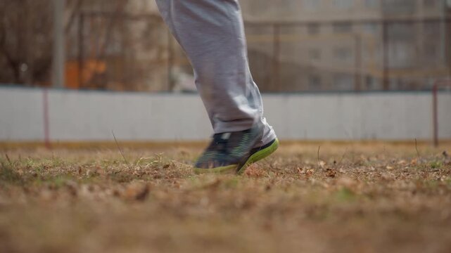white player performing quick dribble trick and controlled touch over soccer ball on brown pitch, dynamic foot movement and sneaker contact, casual game atmosphere, close technical focus
