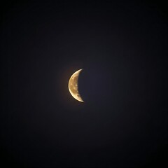 A glowing golden crescent moon, revealing its cratered surface, isolated against the vast, deep indigo expanse of the night sky