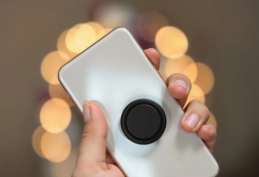 Hand holding white phone with black pop socket mockup, ai generated. Empty circle sticky pad on electronics device for arm mock up, beige background. Clear plastic sticked grip template.