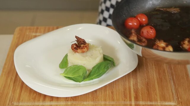 Plating and presentation of celery root puree with fried shrimp and cherry tomatoes