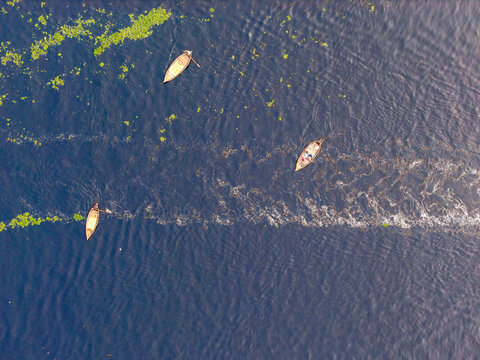 Aerial view of boats gently glide through the dark blue waters, contrasting with the bright green vegetation along the edges, Dhaka, Dhaka Division, Bangladesh.