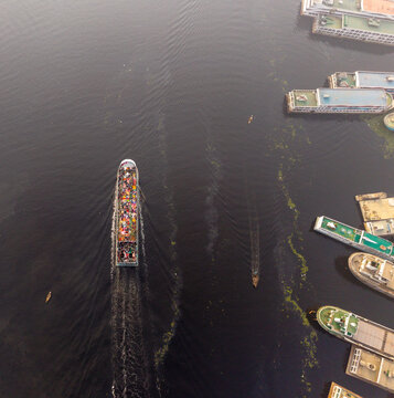 Aerial view of barges and boats create stark lines against the dark water, a dance of industry and nature, Dhaka, Dhaka Division, Bangladesh.