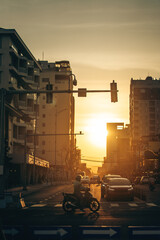 Golden sunset over Da Nang city street with motorbike silhouette, calm urban evening atmosphere, Warm golden hour light over Danang, peaceful city traffic scene with cars and scooter