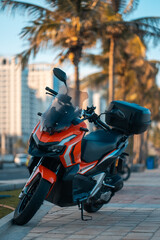 Modern sporty motorcycle parked on tropical city street with palm trees at sunset, Stylish urban motorbike standing on avenue in warm evening travel setting