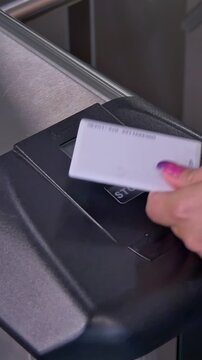 A hand places a white access card on a turnstile reader. A red stop light briefly appears, then a vibrant green arrow illuminates, signaling successful passage through the modern automated gate.