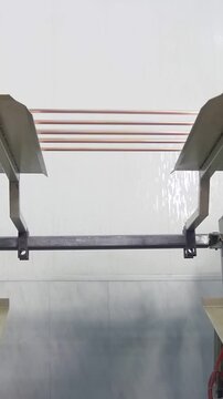 Copper tubing smoothly moves through an intricate industrial framework. Automated mechanisms meticulously handle metal components in a clean, modern facility.