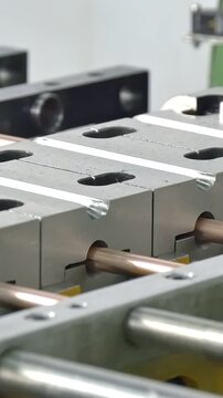 A mesmerizing glimpse into a factory's heart, where slender copper tubes are gracefully integrated into sturdy metal blocks by advanced machinery, a testament to industrial innovation.