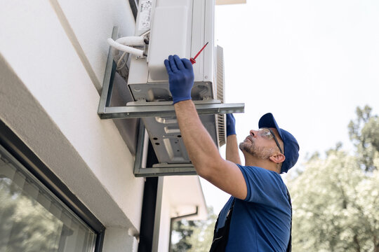 Repairman fixing AC outdoor unit.