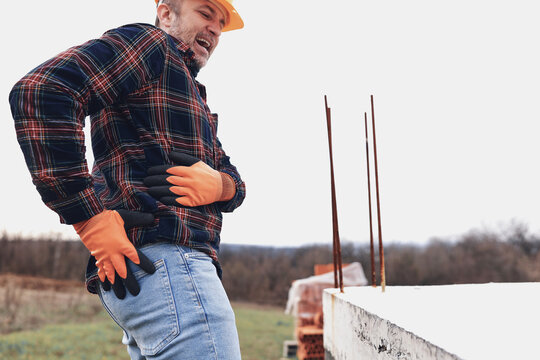 Construction worker having a accident and injured back on a construction site outdoors.