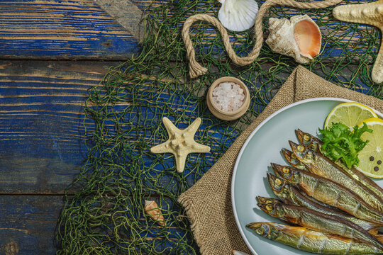 Smoked smelt with fresh lemon and herbs. Salted fish with marine decor. Trendy dish, sea rope