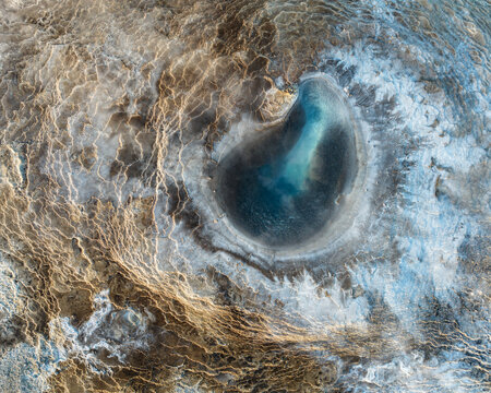 Aerial view of a dark pool surrounded by intricate patterns of light and dark earth, textures creating a captivating mosaic, Reykjavik, Reykjavikurborg, Iceland.