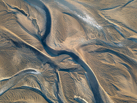 Aerial view of winding glacial rivers carving through the sandy landscape, creating a mesmerizing tapestry of textures and tones, Reykjavik, Reykjavikurborg, Iceland.