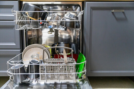 Dirty dish in open integrated dishwasher. Open dishwasher with dirty dishes inside before washing. full loaded dishwasher ready for washing.